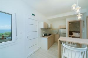 a kitchen with white cabinets and a table and a window at Summer Feelings in Skala Sotiros