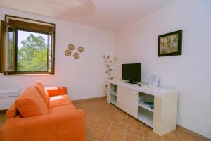 un salon avec une chaise orange et une télévision dans l'établissement Costiera del Cilento Apartments, à Casal Velino