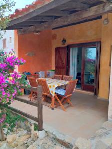 een patio met een tafel, stoelen en bloemen bij Villa bouganville splendido appartamento in Olbia