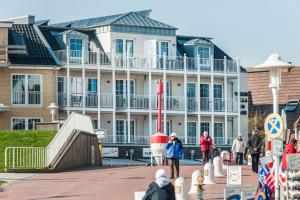 a large building with people standing in front of it at Weisse Villa Apartment 3 2 Annis Strandnest in Büsum