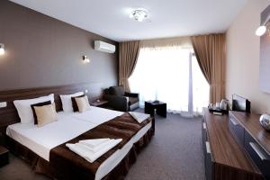 a hotel room with a large bed and a chair at Корал, Хотел, Поморие in Pomorie