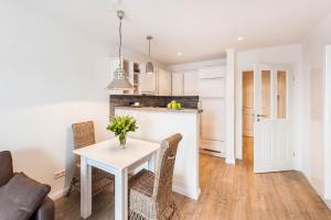 eine Küche und ein Esszimmer mit einem weißen Tisch und Stühlen in der Unterkunft Weisse Villa Apartment 2 3 Deichkind in Büsum