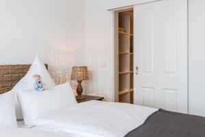 Un dormitorio con una cama blanca con un oso de peluche en la almohada en Weisse Villa Apartment 2 4 Estelles Beachhouse en Büsum