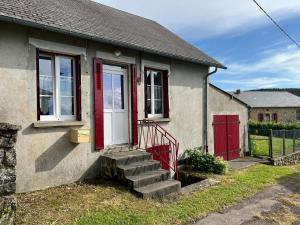 mały dom z czerwonymi drzwiami i schodami w obiekcie Maison au coeur du Morvan w mieście Arleuf