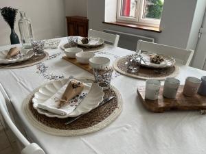 - une table blanche avec des assiettes et de la vaisselle dans l'établissement Maison au coeur du Morvan, à Arleuf