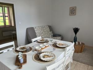 - une table blanche avec des assiettes et de la vaisselle dans l'établissement Maison au coeur du Morvan, à Arleuf