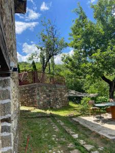 a stone wall with a bench and a table at Cottage Modrich in Struga