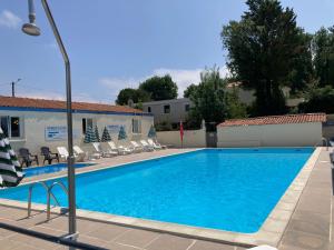a large swimming pool with chairs and a building at Cosy Lili - Mobilhome MANDARINE - Proche océan in Saint-Georges-de-Didonne