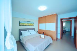 MelíssionにあるNEW TIMES SEAFRONT HOTEL APARTMENTS MELISSIの白いベッド1台(木製ヘッドボード付)が備わるベッドルーム1室が備わります。