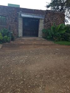 a garage with a stone building with a door at Croc Lapa Chalet in Malelane