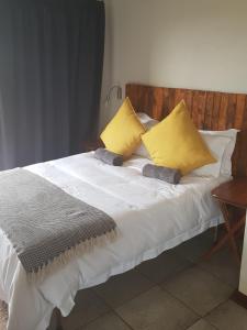 a white bed with yellow and gray pillows on it at Croc Lapa Chalet in Malelane