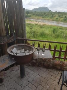 a tub with two wine glasses and a view of a river at Croc Lapa Chalet in Malelane