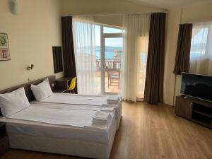 a bedroom with a bed and a television and a balcony at Family Hotel Dreams in Sozopol