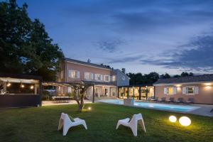 uma casa com um quintal com cadeiras brancas e uma piscina em Villa Green Frame em Butkovići
