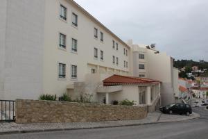 Un bâtiment blanc avec une voiture garée devant. dans l'établissement Hotel Santa Maria, à Alcobaça