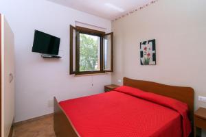 a bedroom with a red bed and a television at Costiera del Cilento Apartments in Casal Velino
