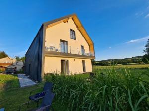 a house with a triangular roof on top of a field at Apartamenty Boczna 3B z sauną i balią in Kudowa-Zdrój