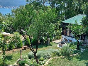 a garden with a house with a tree and a bench at Apartmani VERONA in Bijela