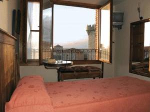 a bedroom with a bed and a large window at Palacio Duque de Tamames - HOTEL EL RASTRO in Ávila