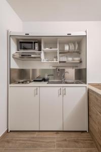 a white kitchen with a sink and a microwave at My Oneiro City Apartments in Ioannina