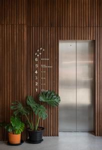 an elevator with two plants in front of a door at Goose Living in Bangkok