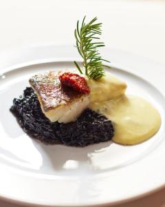 a white plate with a piece of meat and sauce at Azul Beach Resort Montenegro by Karisma - All Inclusive in Ulcinj