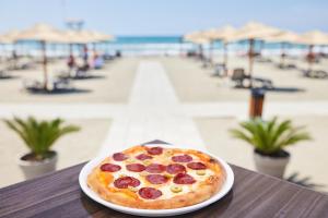 a pizza sitting on a plate on a table near the beach at Azul Beach Resort Montenegro by Karisma - All Inclusive in Ulcinj