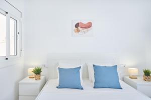 a white room with a bed with blue pillows at Lovely 2 bedroom apartment with terrace in Blanes