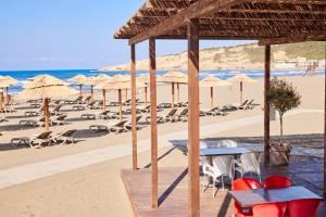 a beach with tables and chairs and umbrellas at Azul Beach Resort Montenegro by Karisma - All Inclusive in Ulcinj
