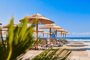 a row of chairs and umbrellas on a beach at Azul Beach Resort Montenegro by Karisma - All Inclusive in Ulcinj