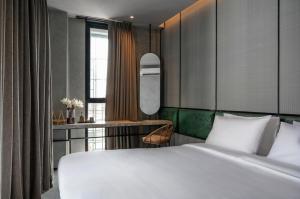 a bedroom with a large white bed and a desk at Goose Living Bangkok BTS Phra Khanong in Bangkok