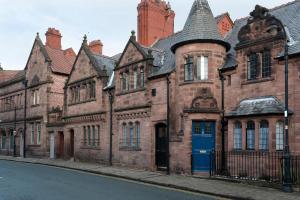 um velho edifício de tijolos com uma porta azul numa rua em In the Heart of Chester, Historical & Stylish em Chester