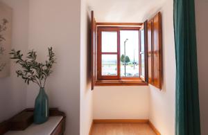 un vase assis sur une table à côté d'une fenêtre dans l'établissement FLH Alfama Flat with River View, à Lisbonne