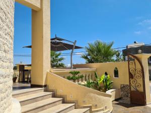 a house with stairs and an umbrella on the roof at Mahdia - Baghdadi - Laourient Apartments, restaurant, café in Mahdia
