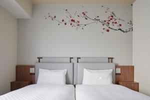 Dos camas con sábanas blancas y un mural de pared de un cerezo. en Via Inn Hakataguchi Ekimae, en Fukuoka