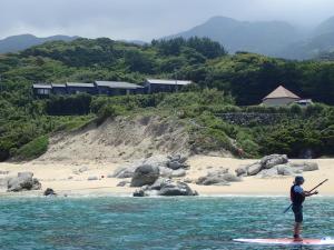 a man is standing on a paddle board in the water at 一棟貸　屋久の子の家 in Yakushima