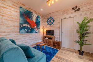 ein Wohnzimmer mit einem blauen Sofa und einem TV in der Unterkunft Le relais des bains in Paladru
