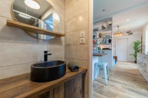 ein Bad mit einem schwarzen Waschbecken und einem Spiegel in der Unterkunft Le relais des bains in Paladru