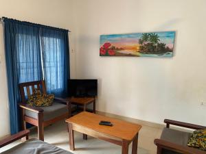 a living room with a table and a painting on the wall at Queen Zee Boutique Hotel in Kololi