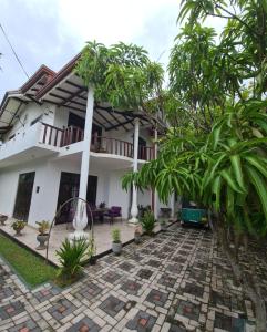 a white house with trees in front of it at Ja-Elas French Touch in Ja-Ela