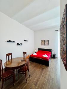 1 dormitorio con cama roja, mesa y sillas en B&B letterario Palazzo Pistocchi en Teramo