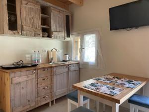 a kitchen with wooden cabinets and a table and a television at Anastasia’s Apartment in Sinarádes