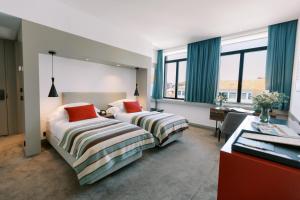 a hotel room with two beds and a desk at The Editory Artist Baixa Porto Hotel in Porto