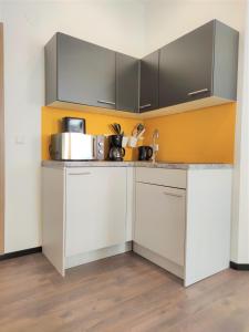 a kitchen with white cabinets and a yellow wall at Studio Hadersdorf near Train station with Free Parking in Hadersdorf am Kamp