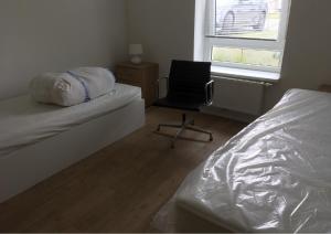 a bedroom with a bed and a chair and a window at SITE.INN Hamburg in Hamburg