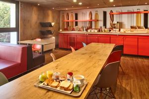 una larga mesa de madera con una bandeja de comida. en B&B HOTEL Versailles Le Chesnay, en Le Chesnay