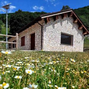 Le Tre Dimore - Rifugio Aceroni في San Biagio Saracinesco: منزل حجري في حقل من الزهور