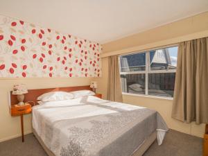 una camera da letto con un letto grande e una finestra di Linton's Sunshine Retreat - Whangamata Home a Whangamata