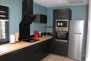 a kitchen with black cabinets and a stainless steel refrigerator at le coin des hirondelles in Pontorson