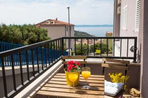 a balcony with two glasses of orange juice and flowers at Apartment Blue Lagoon in Makarska